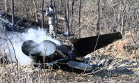 京畿道華城市正南面官項里の山野に墜落したF-5E戦闘機の機体を軍関係者が調べている。／11日、聯合ニュース 