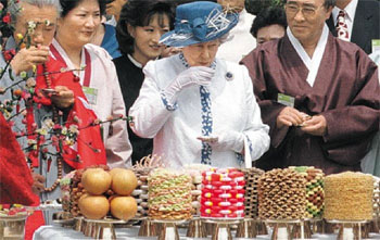 ▲1999年、韓国を訪れたエリザベス女王。慶尚北道安東市内の民族村「河回村」では誕生日を祝う韓国の宮中料理や菓子などが用意された。写真＝聯合ニュース