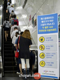 ▲今月19日午後、ソウルの地下鉄・光化門駅のエスカレーターで。「2列乗り」を呼び掛ける案内看板が立っているが、利用者たちは依然として左側を空けて乗っている。／写真＝キム・ジホ客員記者