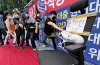 ▲ソウル市中区の預金保険公社前で25日、政府による厳しい不動産規制策に抗議して開かれたろうそく集会で参加者が文在寅大統領の名前が書かれた椅子に靴を投げるパフォーマンスを行っている。／コ・ウンホ記者