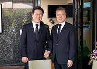 ▲23日、慶尚南道金海市進永邑烽下村にある故・盧武鉉（ノ・ムヒョン）元大統領の私邸で行われた非公開の昼食会で、文在寅（ムン・ジェイン）前大統領にあいさつして写真を撮る共に民主党の李在明（イ・ジェミョン）総括選挙対策委員長・国会議員補選仁川市桂陽区乙選挙区候補者。写真提供＝李在明候補選挙陣営