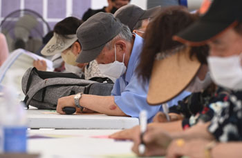 ▲21日午後、京畿道水原市八達区の華城行宮広場で行われた「高齢者雇用採用会」を訪れ、求職申請書を作成する高齢者たち。写真＝NEWSIS