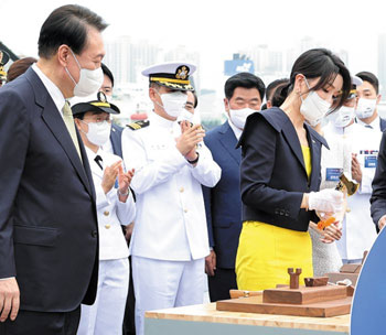 ▲28日に蔚山の現代重工業で開かれたイージス艦「正祖大王」の進水式で、尹錫悦大統領が見守る中、金建希（キム・ゴンヒ）夫人が金色のおので支綱を切っている様子。／写真＝韓国大統領室