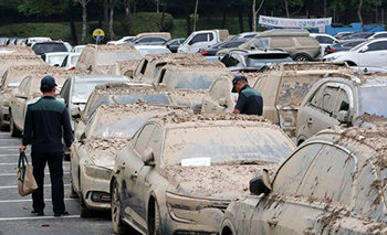 ▲22日、京畿道果川市内のソウル大公園駐車場で、冠水の程度や車両登録証、車の鍵の有無など、冠水車（水没車）の状態を確認する保険会社の社員。写真＝ナム・ガンホ記者
