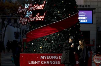 ▲ソウル市中区明洞に設置されたクリスマスツリーの前で旅行客が楽しんでいる。／18日午後、NEWSIS