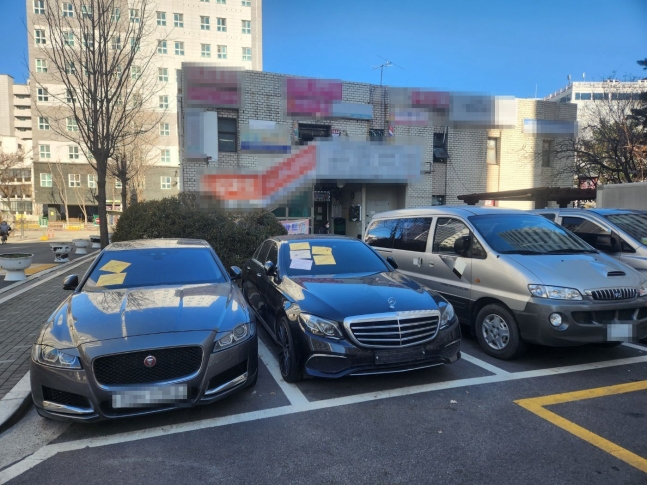 ▲16日午後、ソウル市江西区のあるマンションの駐車場で。無断駐車の中古車2台に「駐車違反警告状」というステッカーが貼られていた。写真＝キム・グァンジン記者
