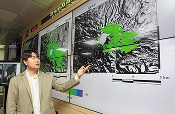 ▲韓国気象庁国家地震火山総合状況室で衛星写真を使い白頭山の地表の変化について比較説明するイ・ハソン気象研究士。11日撮影。／コ・ウンホ記者