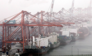 ▲国内外の機関が今年の韓国経済の成長率を下方修正したのは、韓国経済の柱である輸出が長期間にわたり揺らいでいるためだ。写真は霧でかすむ釜山港に積み上げられた輸出入コンテナ。写真＝聯合ニュース