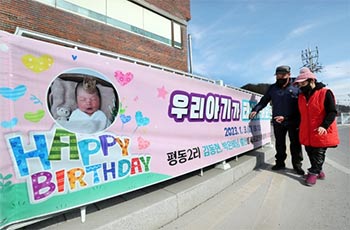▲忠清北道丹陽郡梅浦邑の交番前にかけられた「私たちの子供が生まれました」と書かれたお祝いの横断幕とそれを気分良さそうにみつめる地元住民。2023年2月22日撮影。／シン・ヒョンジョン記者