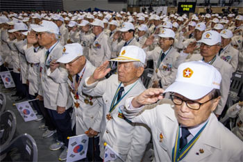 ▲6・25戦争参戦勇士らが25日、ソウル中区の奨忠体育館で開かれた6・25戦争73周年行事で、国家報勲部から支給された「英雄の制服」を着て、国旗に敬礼している。／聯合ニュース