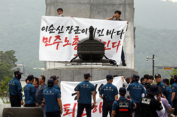 ▲12日午前、李舜臣の銅像に上ってデモを行う民主労総のメンバーら（写真＝NEWSIS）