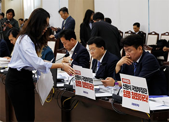 ▲ソウル市竜山区の韓国国防部（省に相当）庁舎で今月10日に開催された国会国防委員会による国政監査。議員席に貼られた「不適格シン・ウォンシク国防長官任命を撤回せよ！」と書かれたプラカードを撤去する野党・共に民主党の関係者。／国会写真記者団