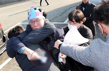 ▲2日午前、釜山市江西区の大項展望台で、李在明・共に民主党代表を襲撃した人物が凶器を持ったまま警察に連行されているところ。／写真＝NEWSIS