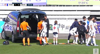 ▲木浦国際サッカーセンターで先月27日に開催された2024・K3リーグの木浦FCと江陵市民サッカー団との試合で負傷したパク・ソンジュ選手を運ぶ江陵の選手とスタッフ。左にはパク選手を病院に搬送するためワゴン車が待機している。／KFATV