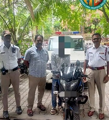 ▲インドで女性を膝の上に座らせて道路を走行するバイクの運転手が警察に捕まったときの様子。／ベンガルール交通警察