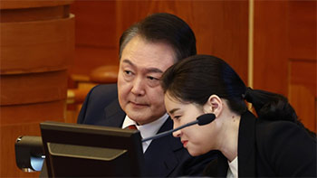 ▲13日、ソウル市鍾路区の憲法裁判所で開かれた弾劾審判の8回目の弁論に出席した尹錫悦大統領（左）が、キム・ゲリ弁護士と対話を交わしている様子。／写真＝憲法裁判所