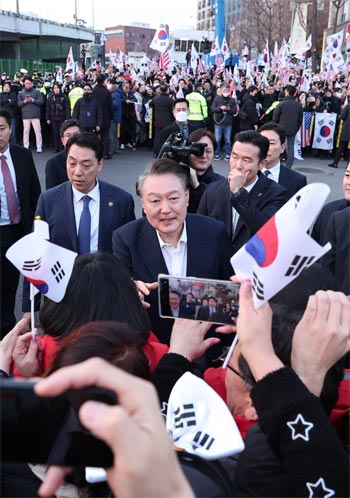 ▲8日、裁判所の拘束取り消し決定により釈放された後、京畿道義王市のソウル拘置所から出て、ソウル市竜山区の大統領公邸前に到着した尹錫悦（ユン・ソンニョル）大統領。支持者たちの方へ近づき、握手をしようとしている。写真＝news 1