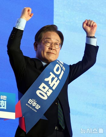 拳を握って突き上げる李在明候補