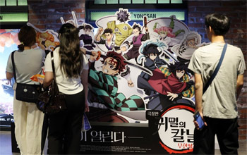 ▲先月31日、ソウル市内のある映画館で、『鬼滅の刃』のパネルを見る人々。写真＝NEWSIS