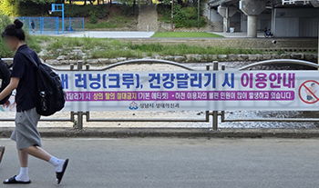 ▲「上半身を脱ぐのは絶対禁止」（黄色い文字）という横断幕が掲げられた京畿道盆唐の散策路を歩く女子高校生。／チョン・サンヒョク記者