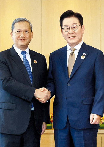 ▲会談前に握手する李在明（イ・ジェミョン）大統領とカンボジアのフン・マネット首相。両首脳はマレーシア・クアラルンプール市内のホテルで首脳会談を行った。27日撮影。／聯合ニュース