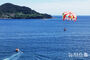 夏の海の上を飛ぶパラセーリング